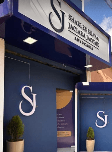 Fachada do escritório em azul-marinho, com o letreiro Sharles Silva & Jaciara Jacome Advocacia e o monograma SJ.